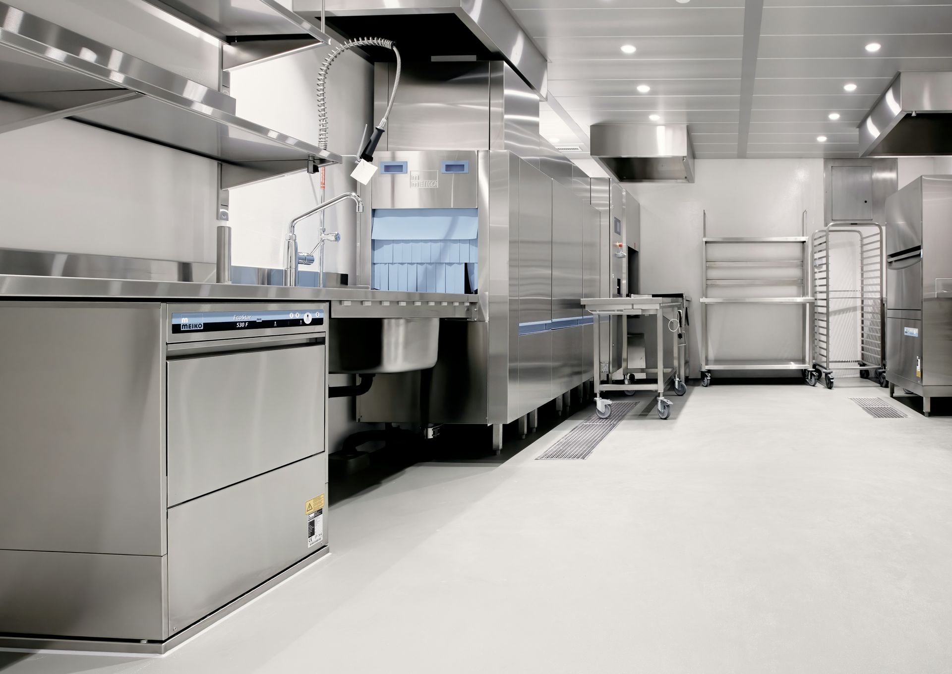 A commercial kitchen with stainless steel dishwashing equipment and metal shelving units